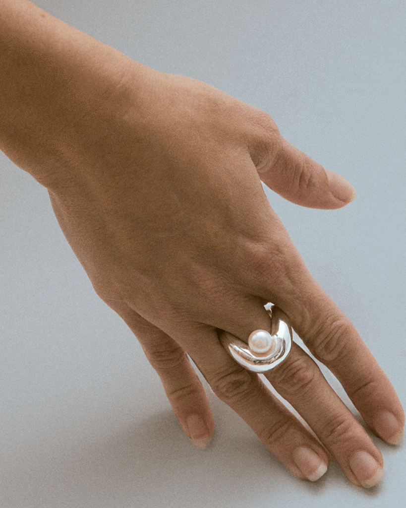 a hand with a pearl ring